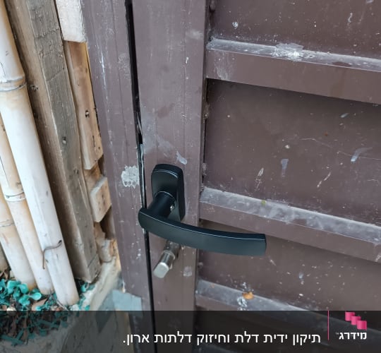 דלת מתכת עם ידית שחורה ובריח כסוף